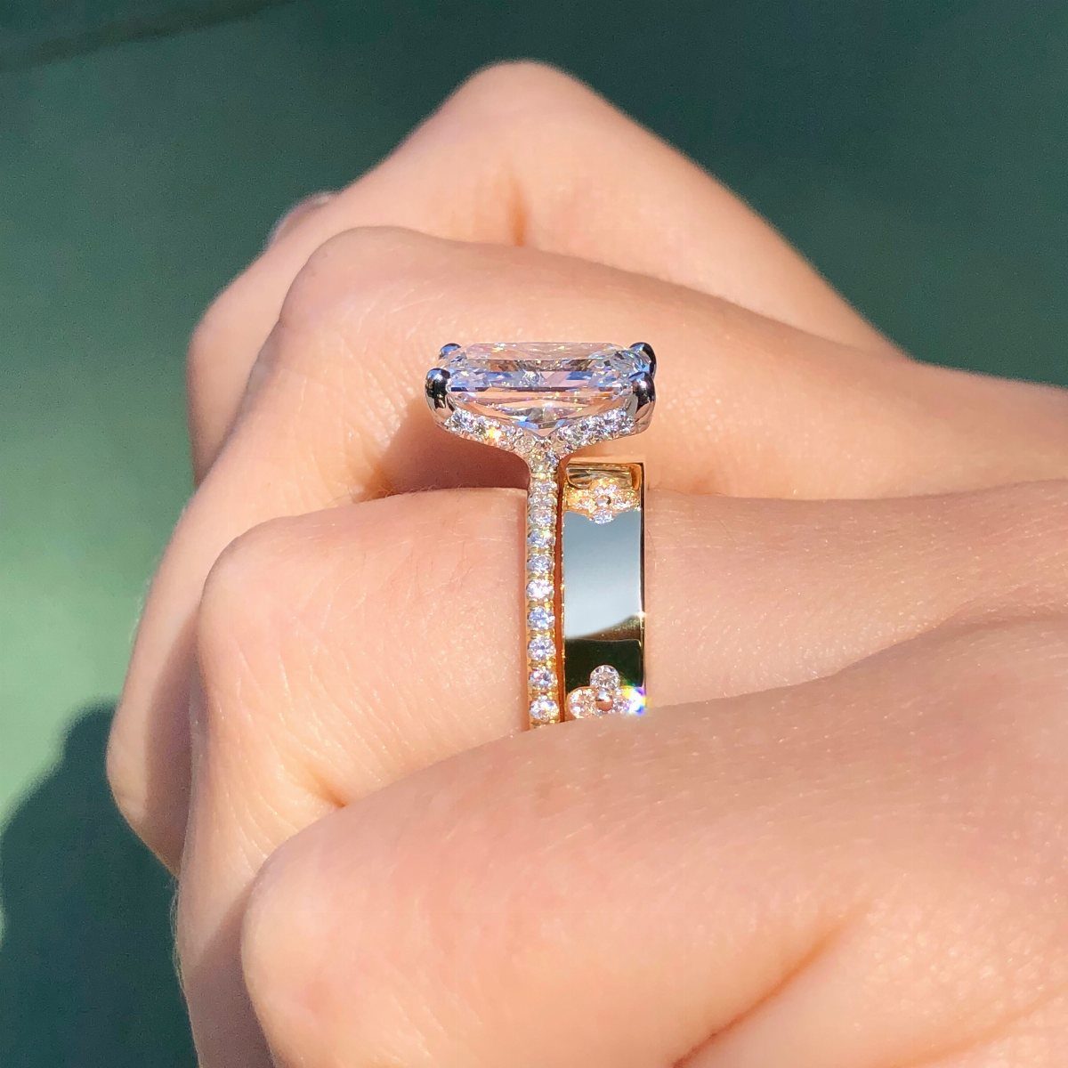 Emerald-cut diamond engagement ring with a halo setting on a gold pavé band