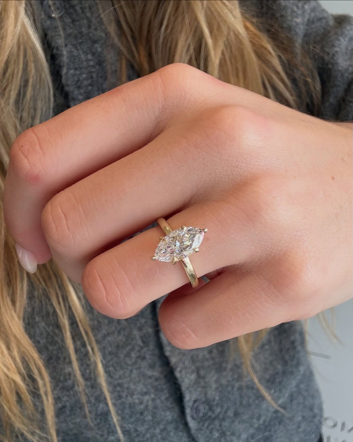 Gold engagement ring with a marquise-cut diamond worn on a person's finger