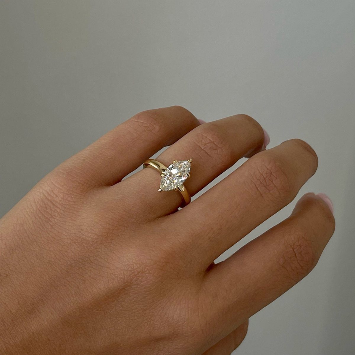 Marquise-cut diamond engagement ring on a gold band worn on a finger