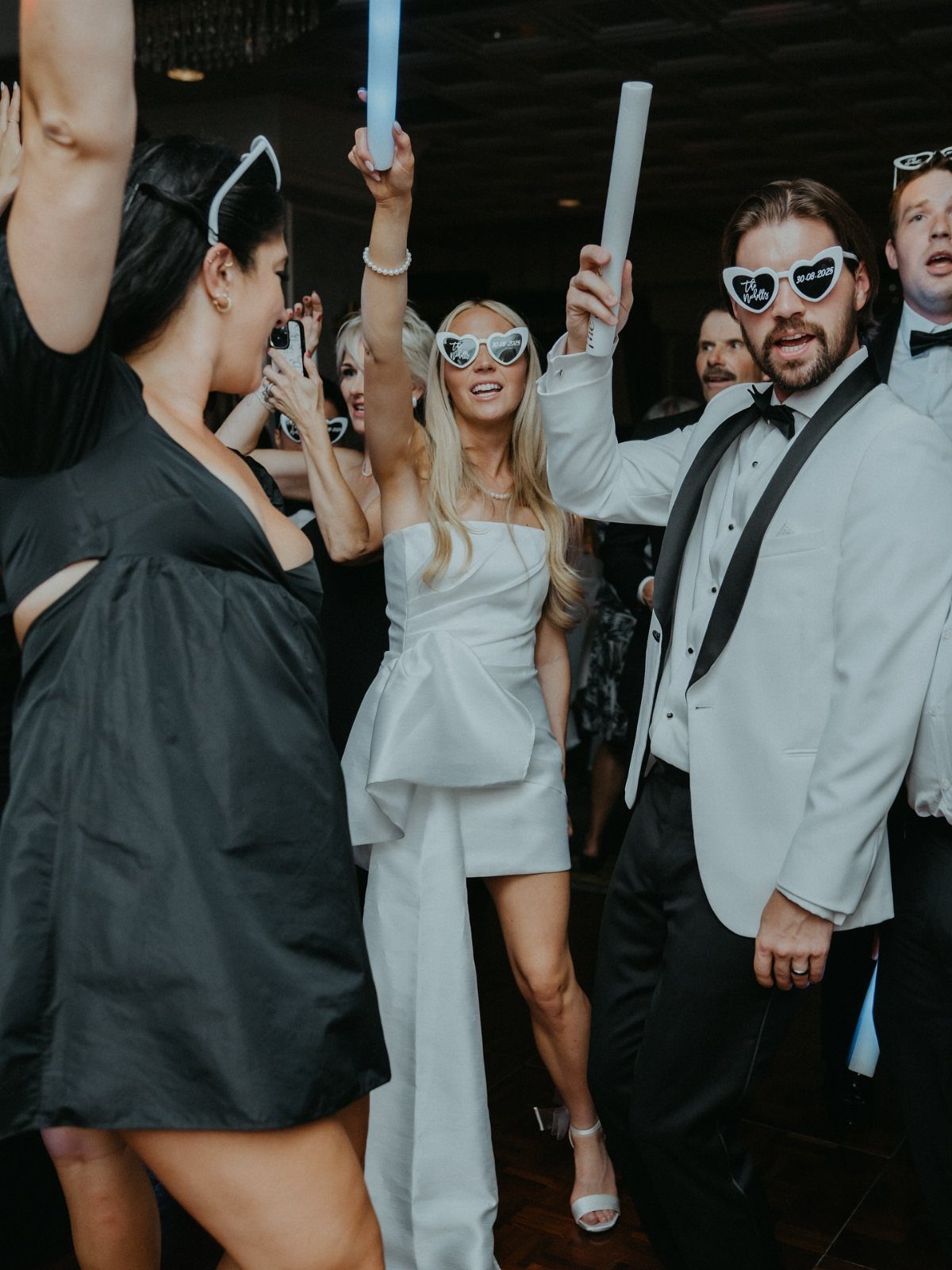 Woman in a short white wedding after party dress dancing with guests.