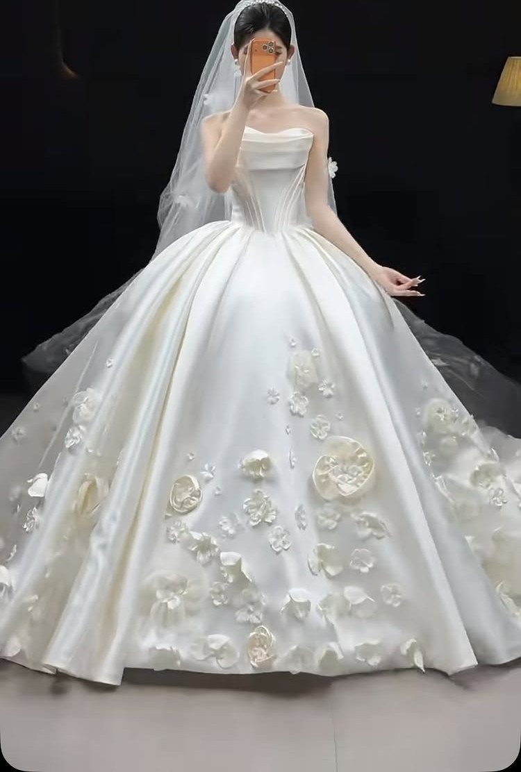 White ball gown wedding dress with 3D floral details and a sheer veil.