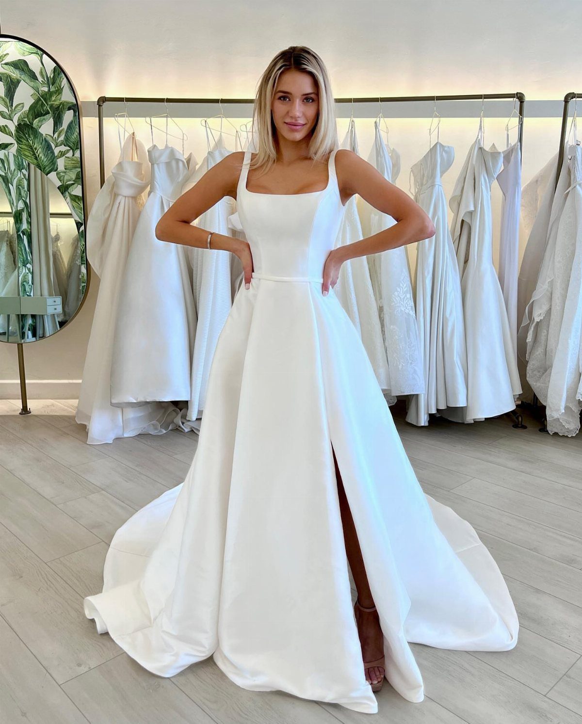 Woman wearing a minimalist white satin wedding dress with a square neckline.