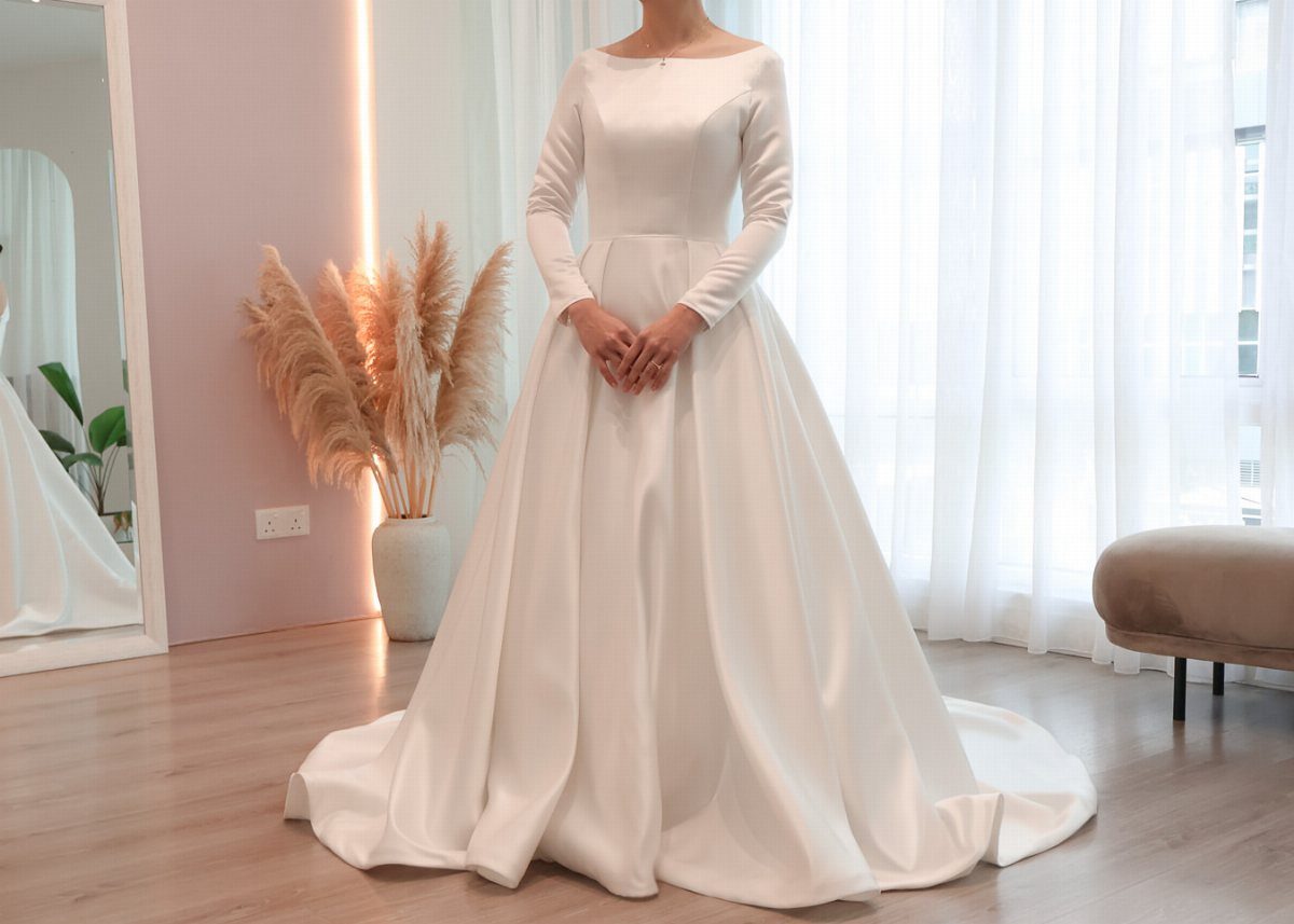 White satin ball gown wedding dress with long sleeves in a bright room