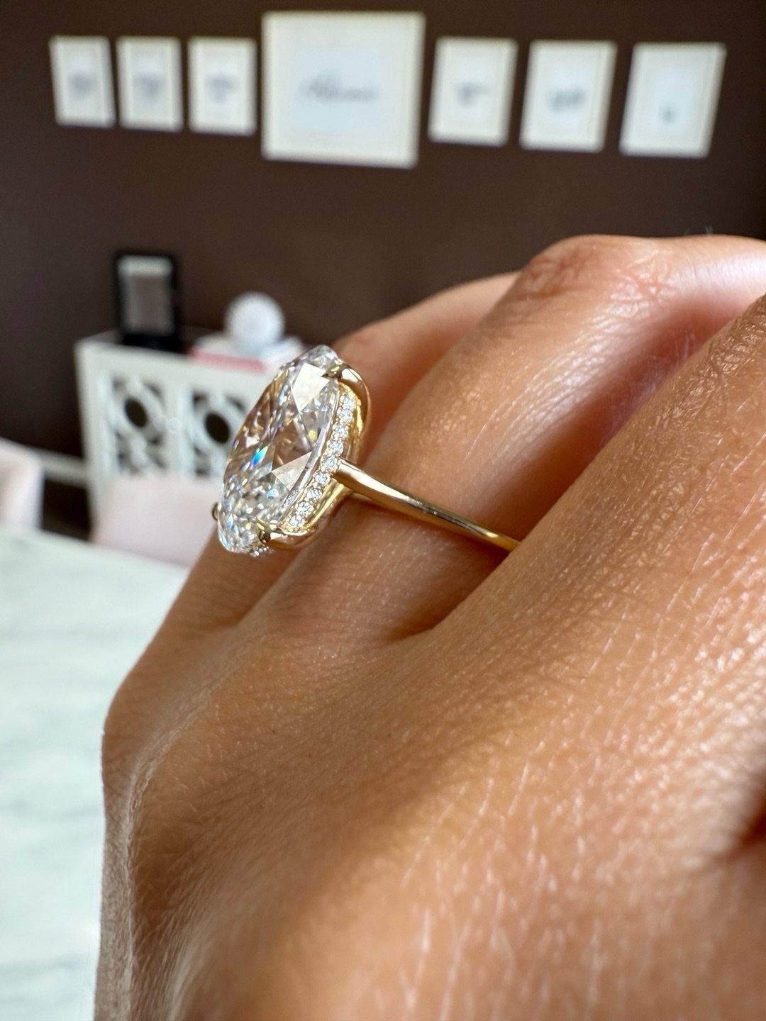 Almond shaped diamond engagement ring with a gold band on a finger