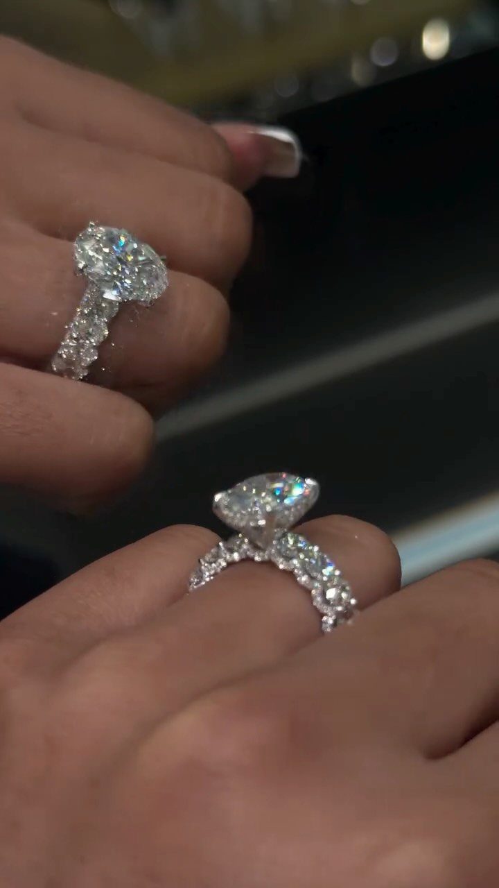 Almond shaped diamond engagement ring with a pavé band on a finger.