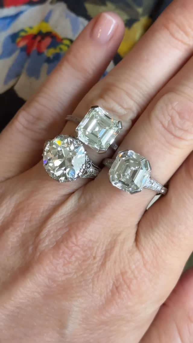 Three diamond engagement rings with different cuts worn on a person's hand.