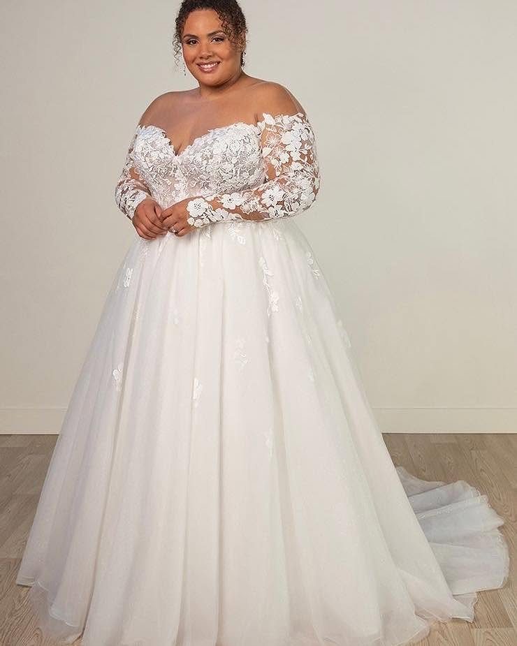 Woman in a big white lace wedding dress with long sleeves and full skirt