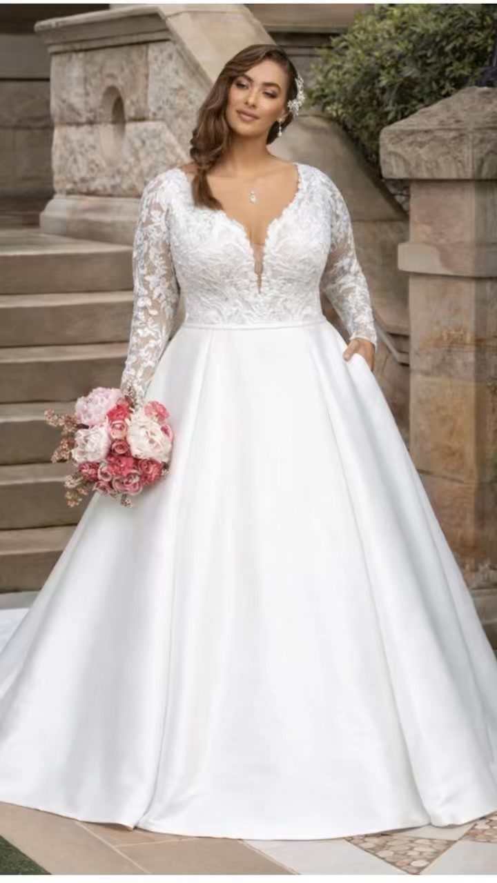 Woman in a white lace wedding dress with a full skirt holding flowers