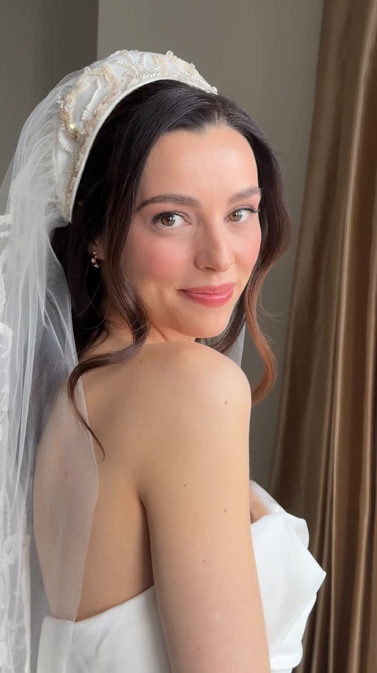 Bride with green eyes wearing a white veil and nude lip color.