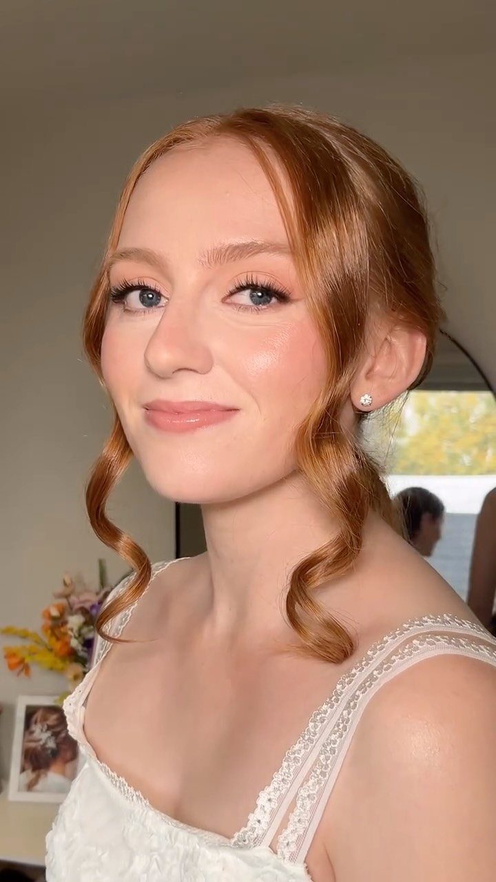 Woman with pale skin and red hair wearing natural bridal makeup and white lace dress