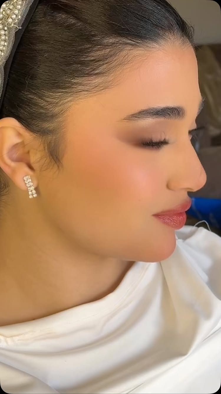Woman with soft glam bridal makeup, neutral eyeshadow, and rose-toned lips in profile.