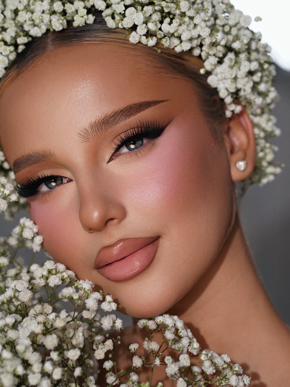 Woman with bridal makeup and a white flower crown posing for a portrait