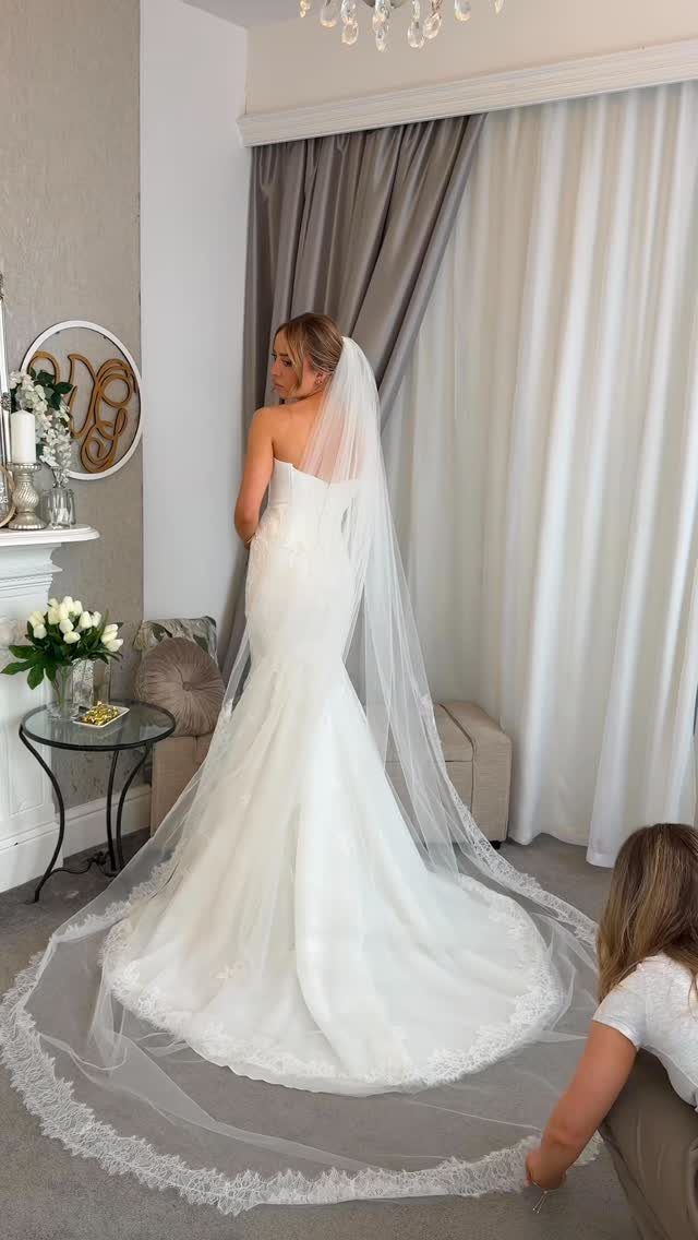 Bride in a white mermaid dress wearing a long cathedral length lace veil.