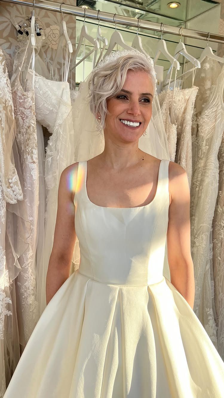 Woman in white bridal gown wearing a sheer veil and beaded headband.