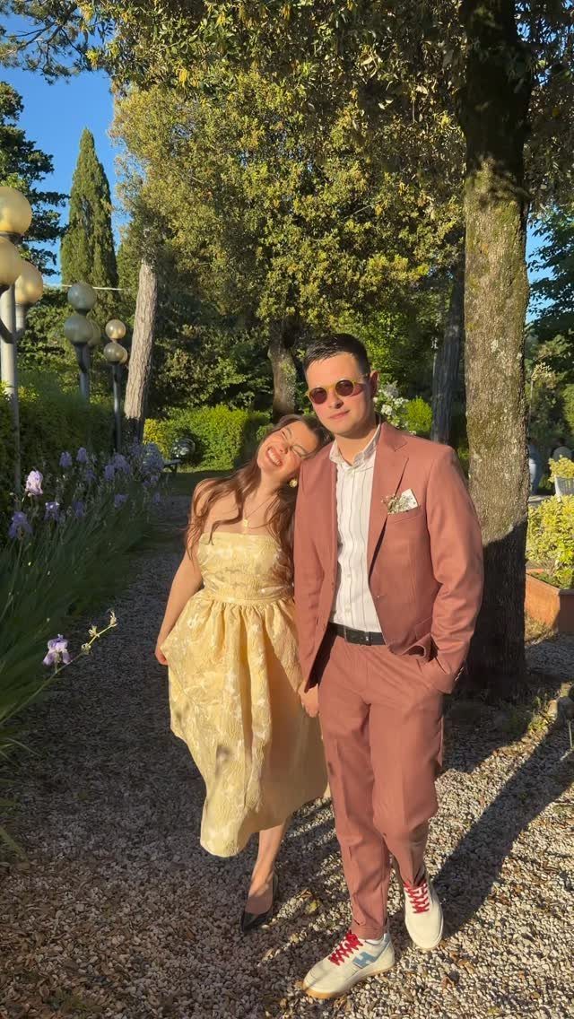 Man in terracotta suit and woman in yellow dress posing in a garden