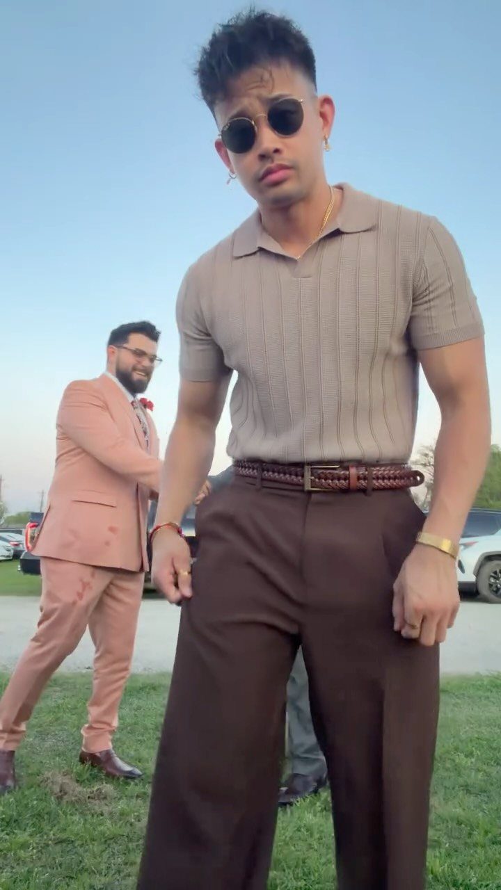 Man wearing a tan polo and brown trousers for a casual wedding guest outfit.