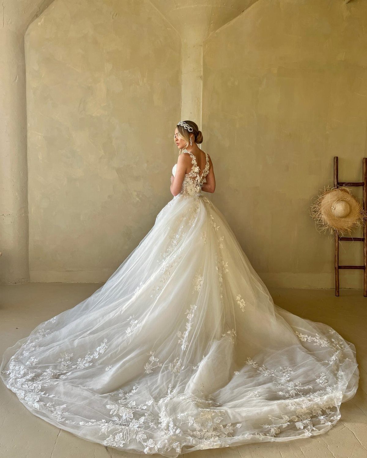 Woman in a white lace wedding dress with a long cathedral train spread out.