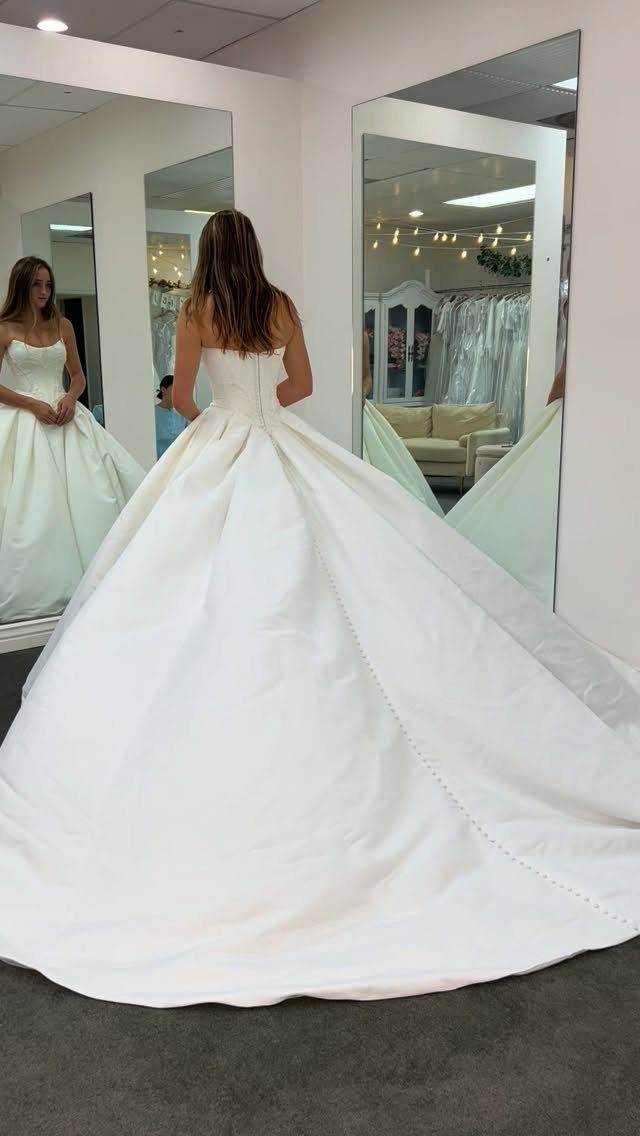 Woman wearing a white wedding dress with a long cathedral train in a boutique