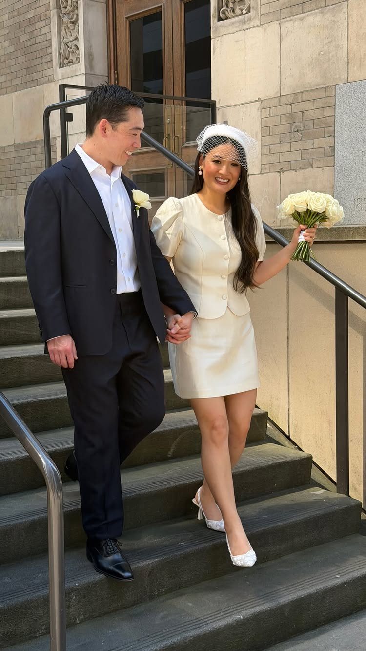 Couple walking down steps, bride wearing a short cream dress and white veil.