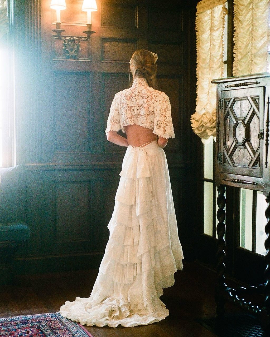 Woman wearing a white lace crop top and tiered bridal skirt in wood-paneled room