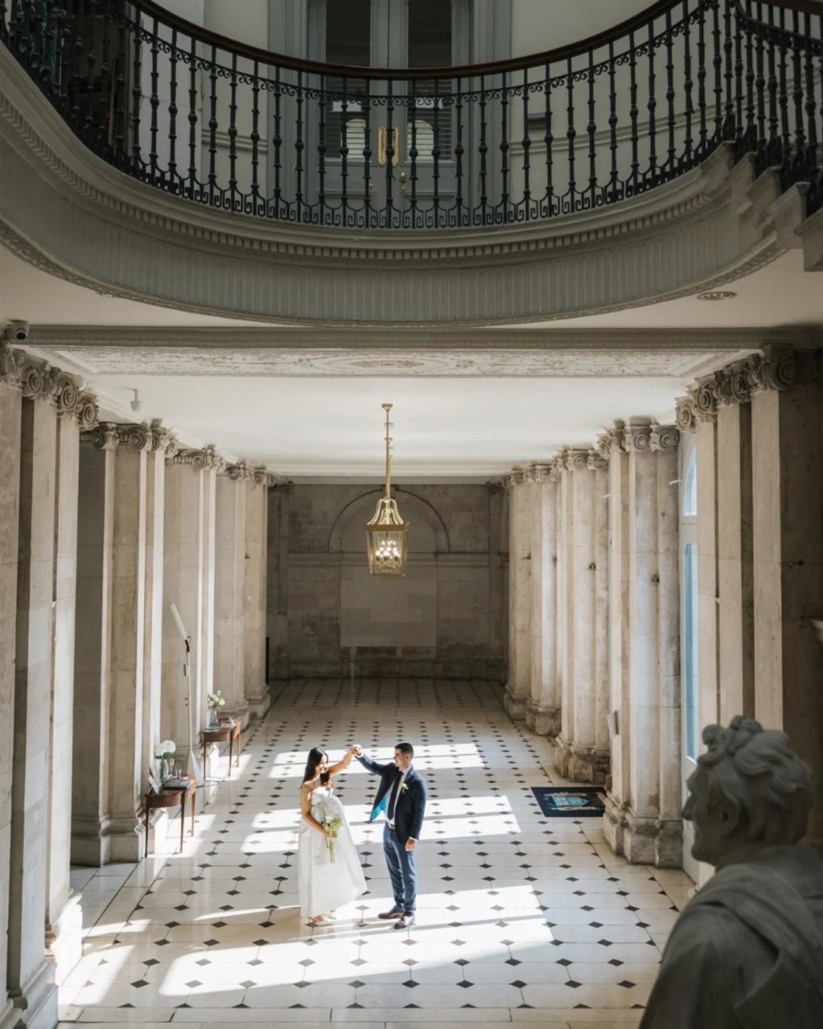 Bride and groom dancing in a grand marble hall with classical columns