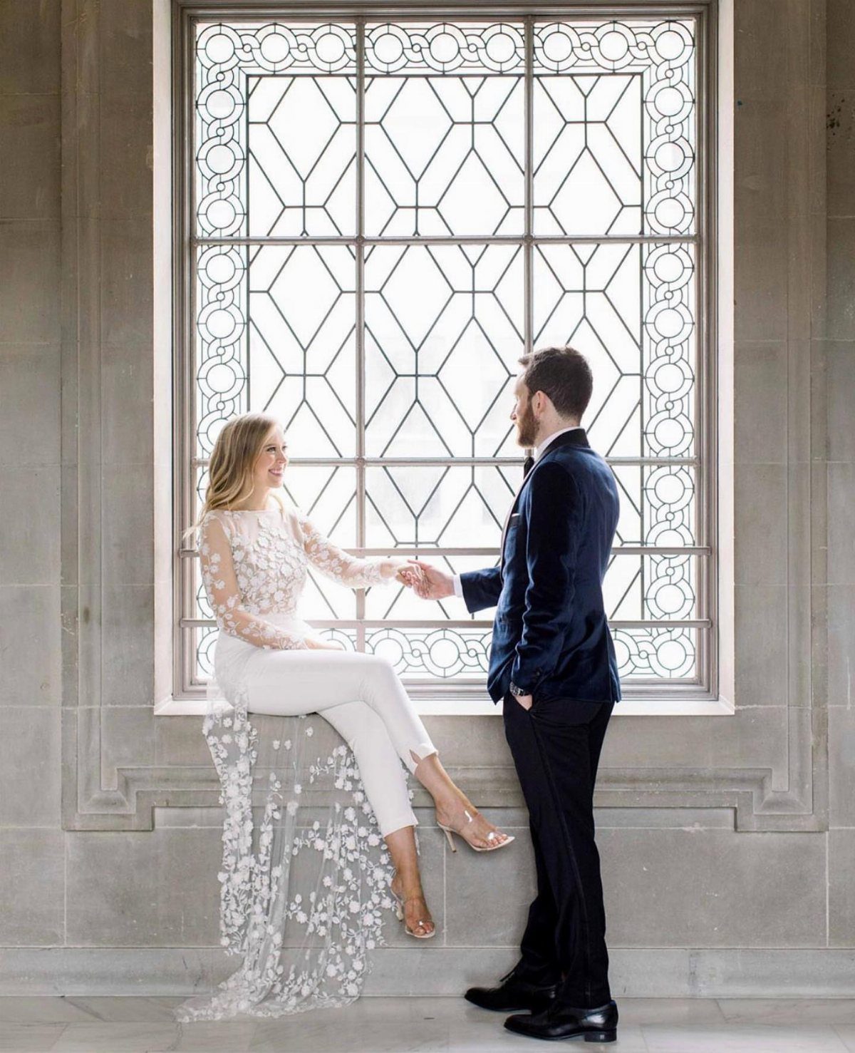 Woman in white tailored bridal jumpsuit and lace top with a groom.