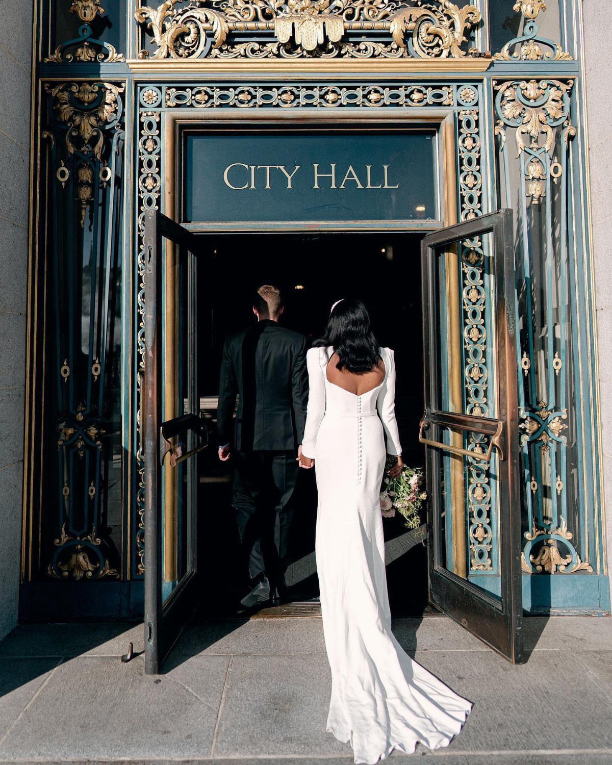 Couple entering City Hall, woman wearing a white floor-length wedding gown