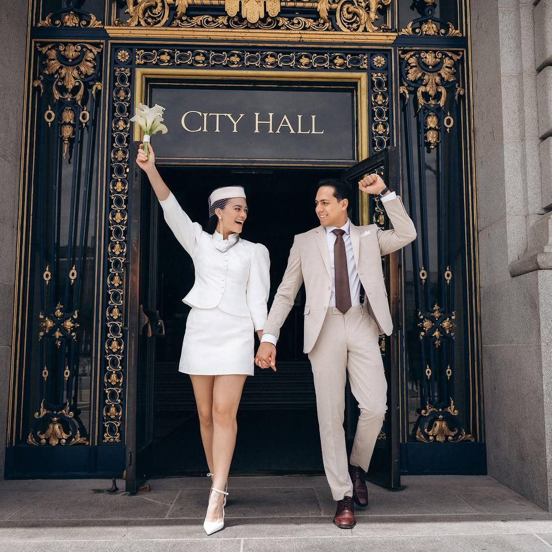 Couple walking out of City Hall, woman in white mini skirt suit set.