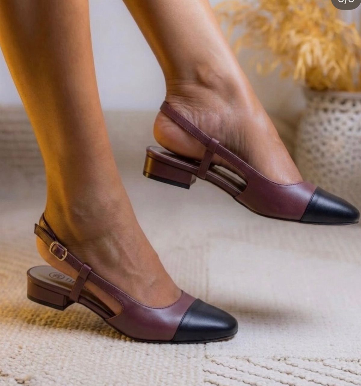 Burgundy and black two-tone slingback pumps with low block heels on a rug.