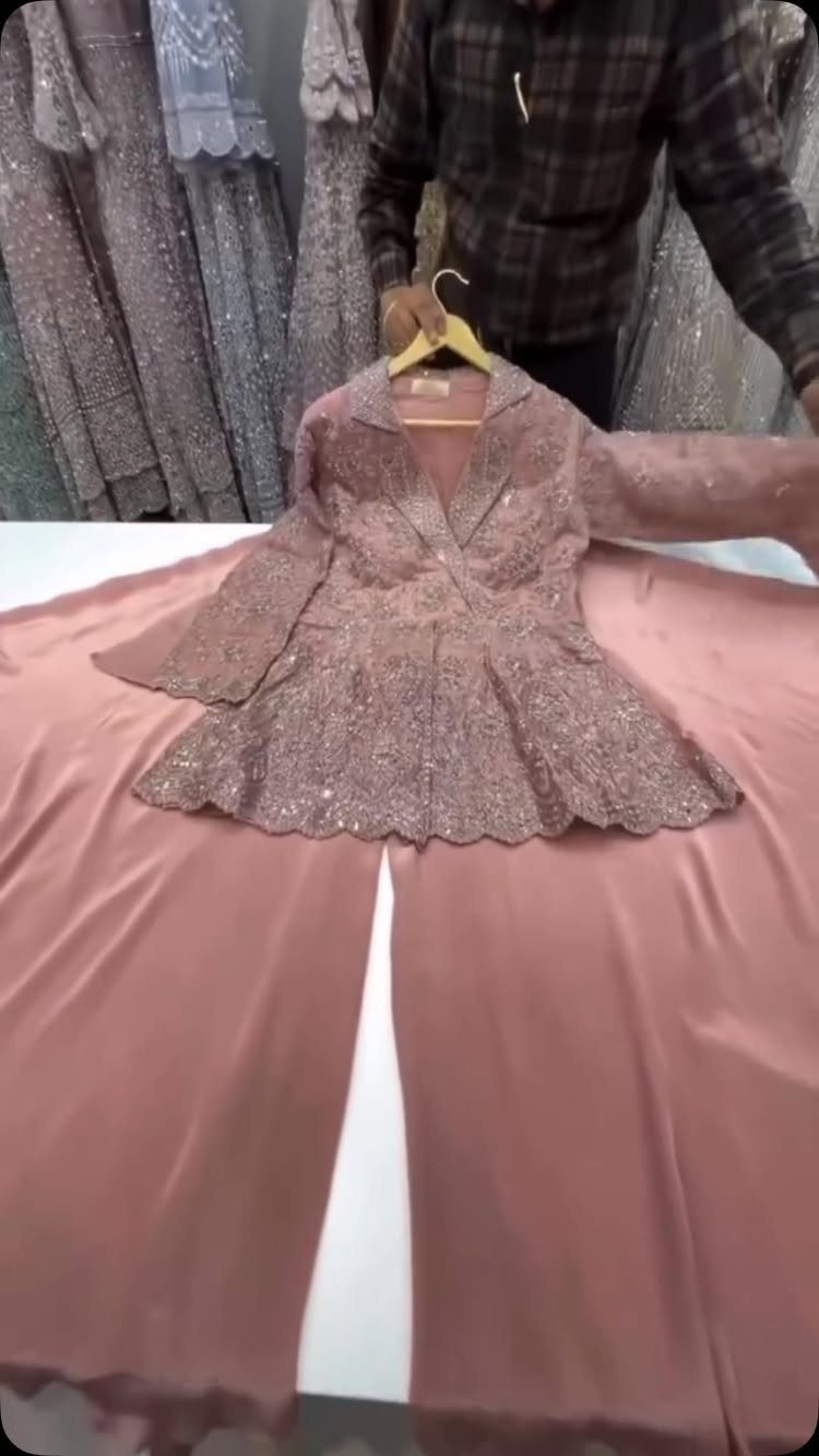 Dusty rose pink embellished peplum top and wide-leg trousers on a hanger.
