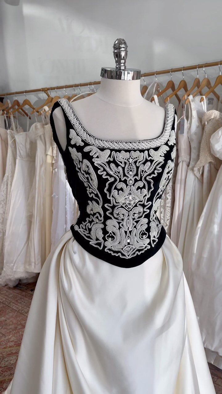White ball gown with a black beaded basque waist bodice on a mannequin.