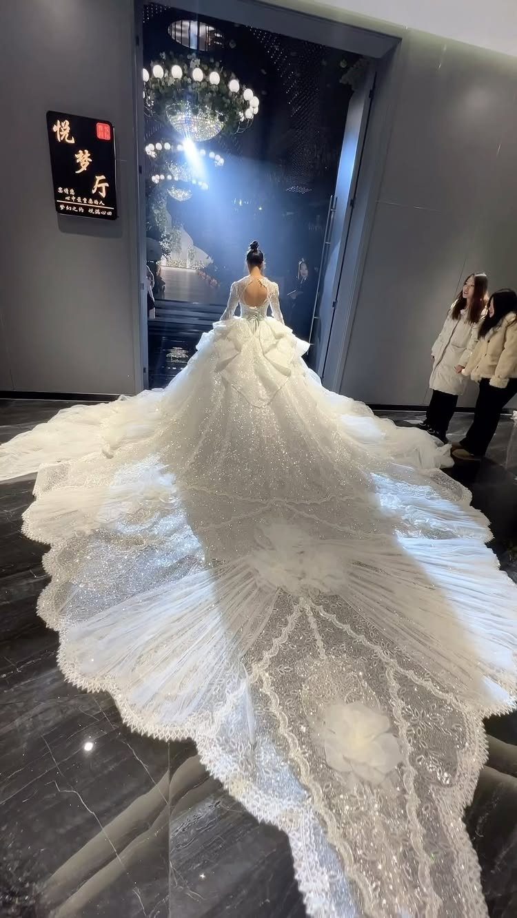 Woman wearing a dramatic white ball gown wedding dress with a massive ornate train.
