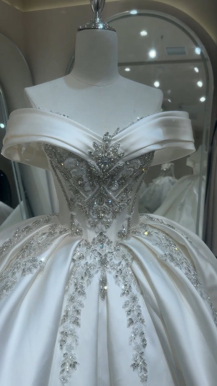White satin ball gown wedding dress with silver crystal embellishments on a mannequin