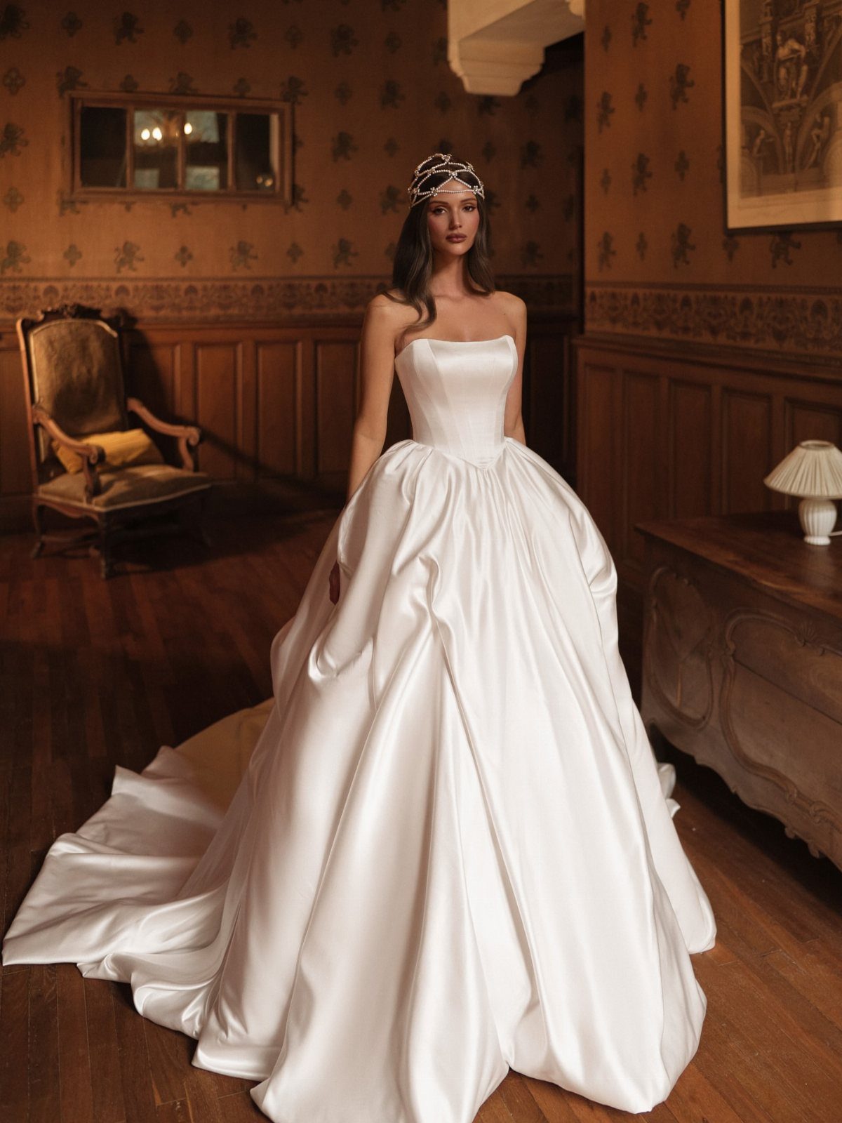 Woman in a voluminous white satin ball gown wedding dress and sparkling tiara.