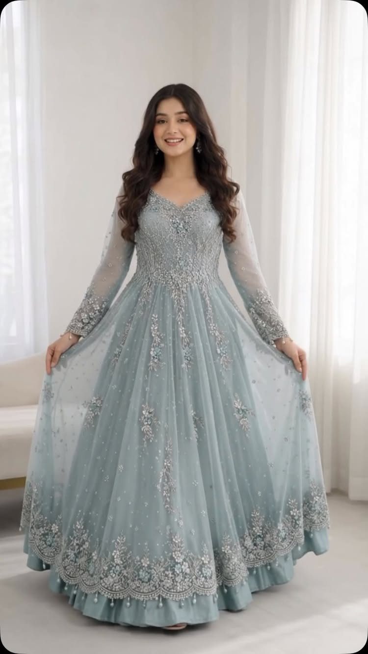 Woman wearing a floor-length light blue gown with silver floral embroidery and sequins.