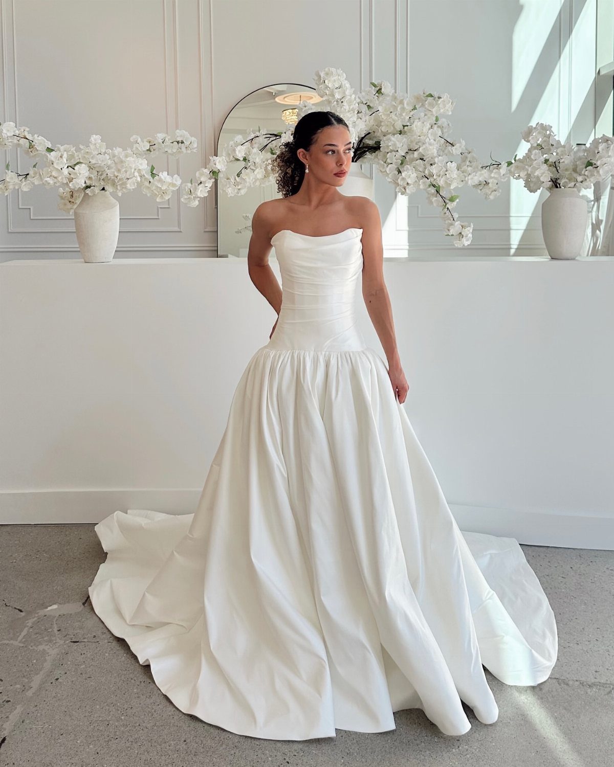 Woman in a strapless white satin drop waist wedding dress with a full skirt