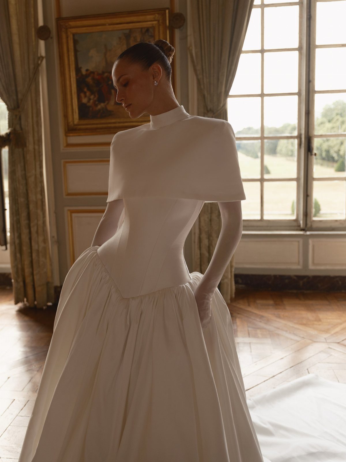 Woman in a white drop waist wedding dress with a capelet in a room