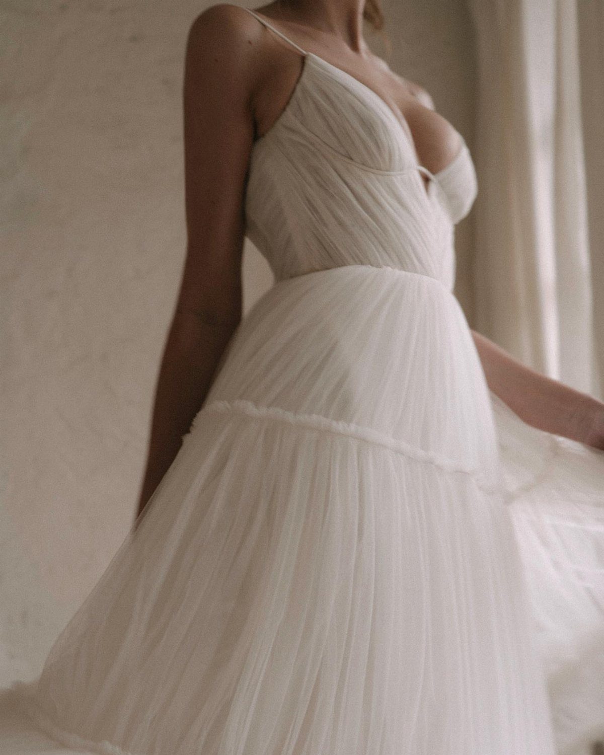 Woman wearing a white drop waist wedding dress with a pleated tulle skirt.