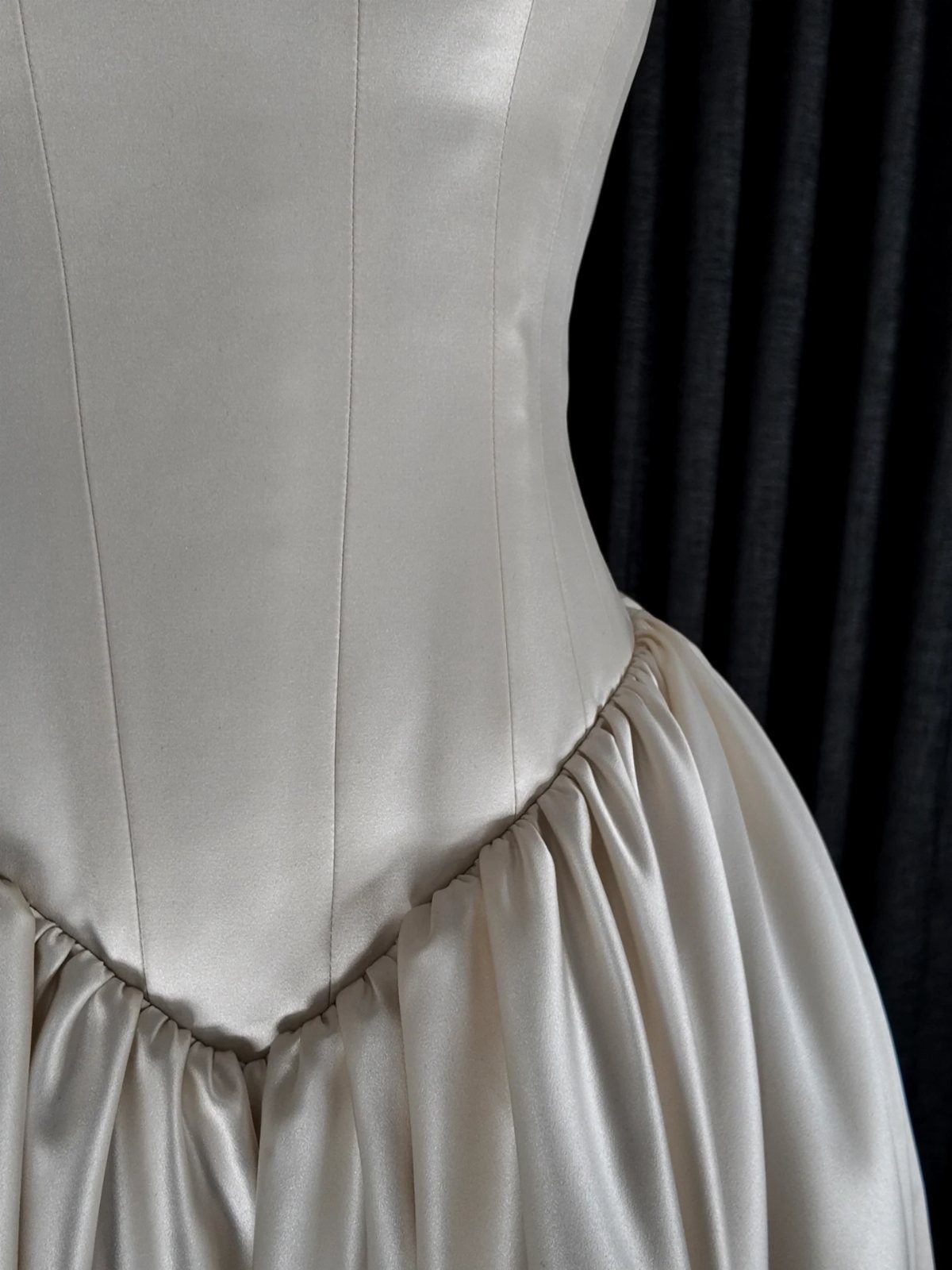 Champagne satin wedding dress featuring a structured bodice and a dropped waistline.
