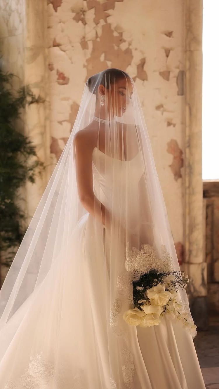 Woman in a flowy white wedding dress wearing a long sheer veil
