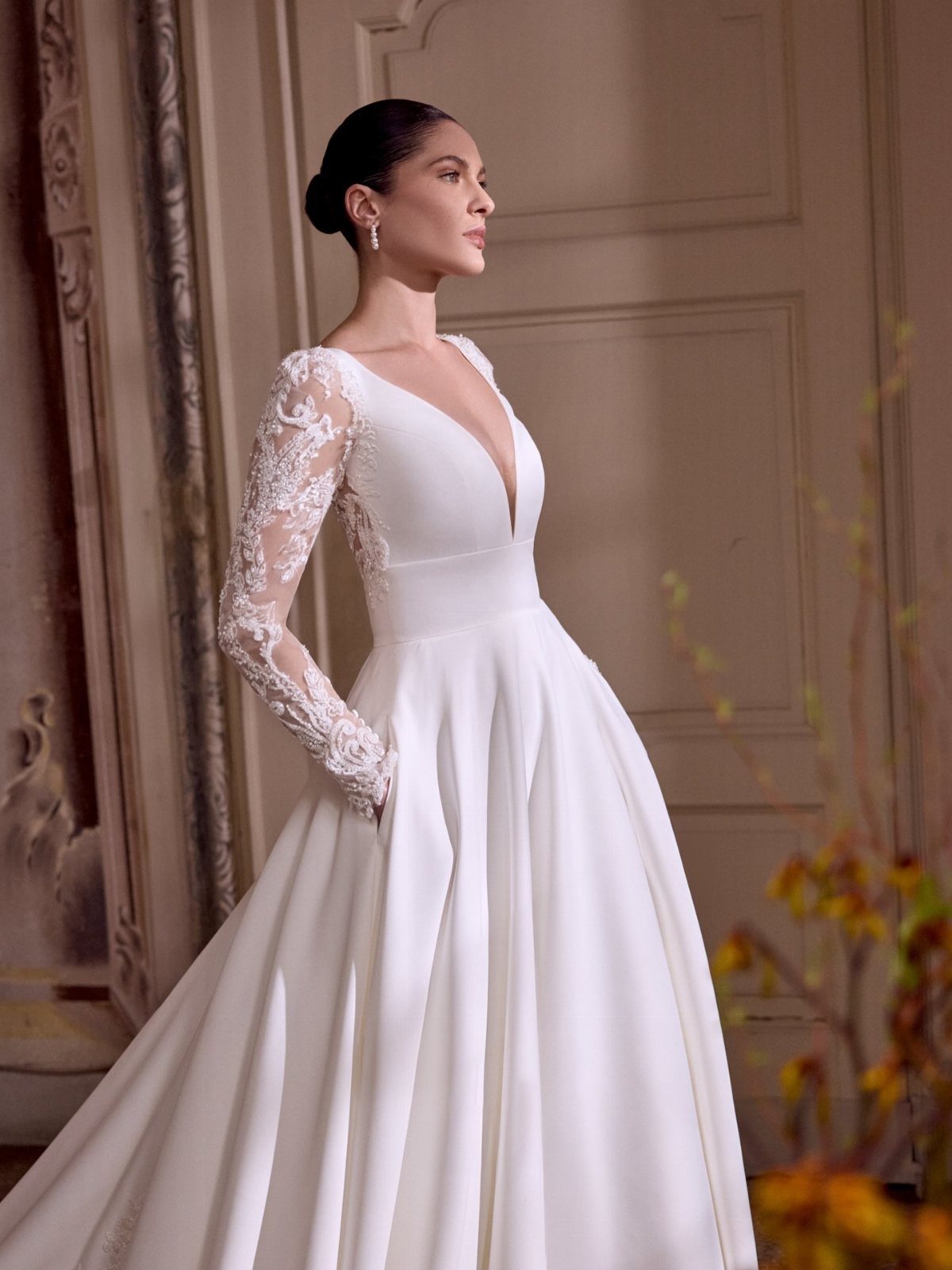 Woman in a white A-line wedding dress with lace sleeves and V-neckline.