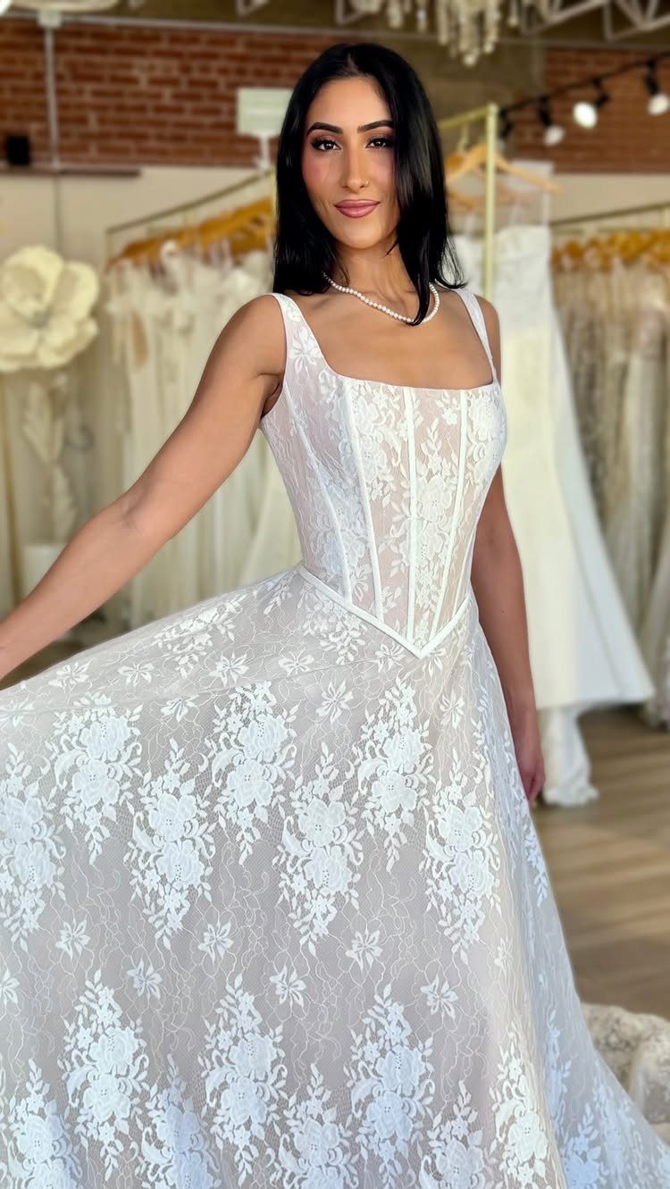 Woman in a white lace wedding dress with a structured bodice in a shop