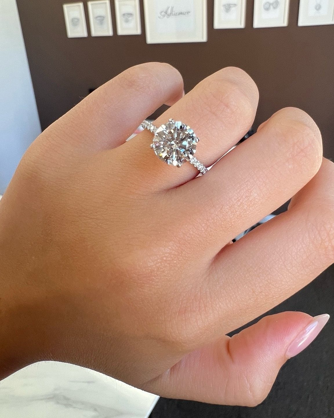 Round diamond engagement ring with a pavé band on a person's finger