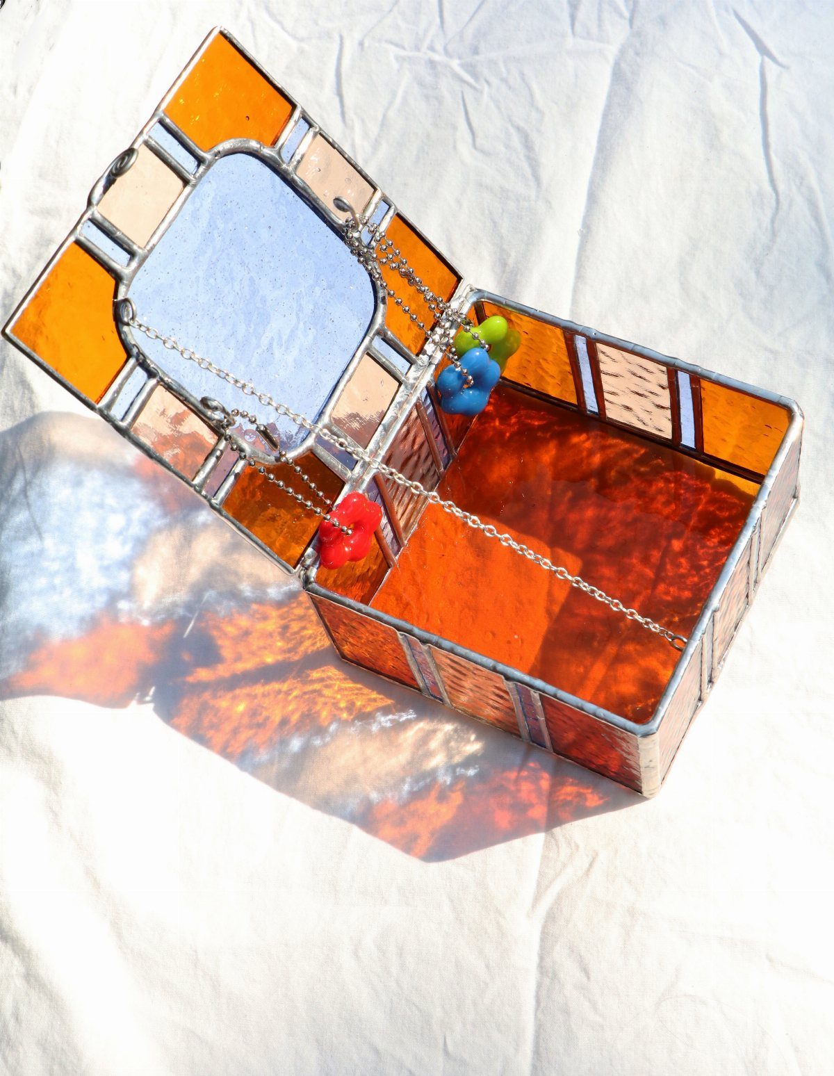 Stained glass box with orange panels and a mirror inside the open lid.