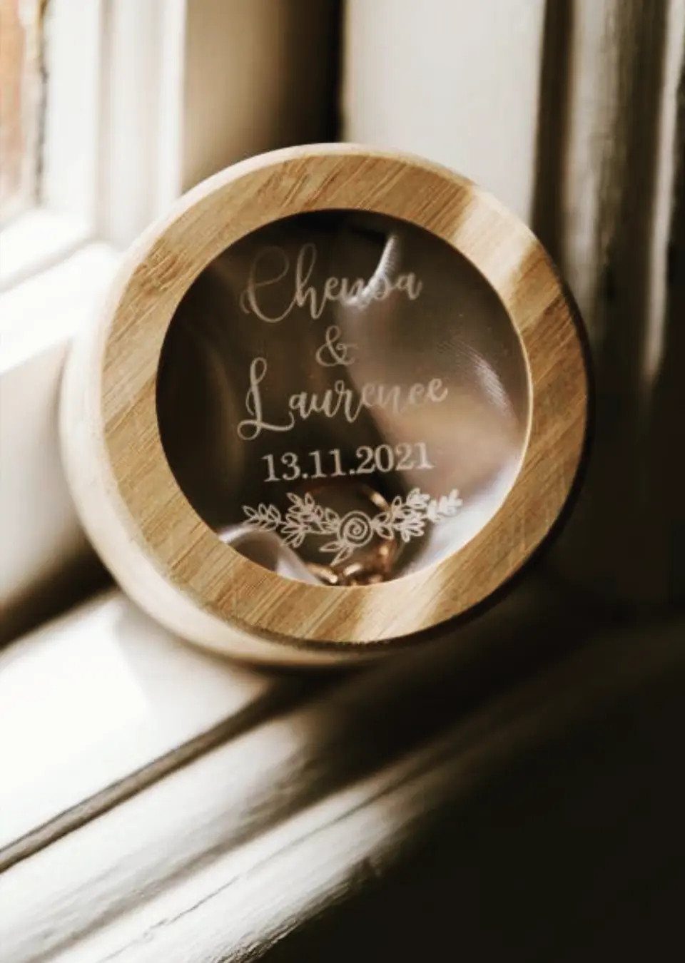 Round bamboo ring box with engraved glass lid and gold ring inside.