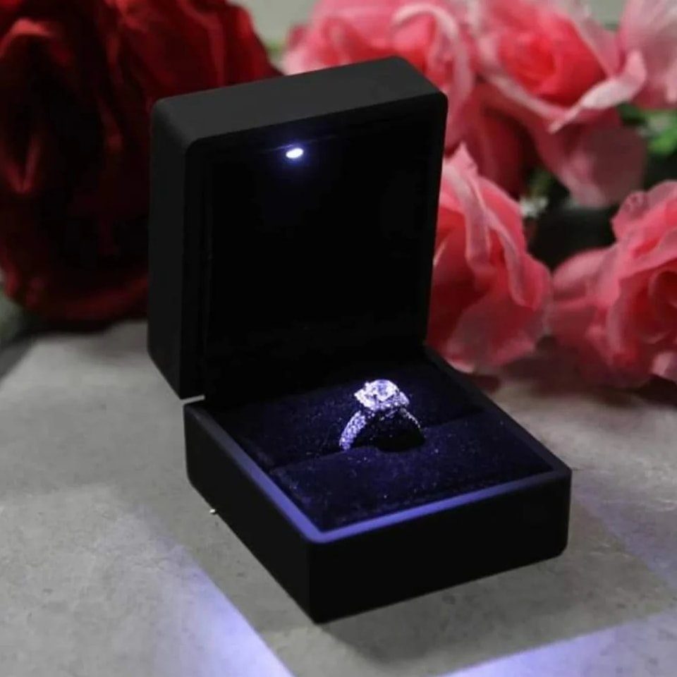 Black velvet ring box with LED light holding a diamond engagement ring