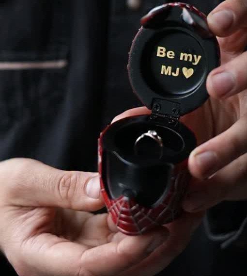 Spider-Man themed red ring box held open showing a diamond ring and text.