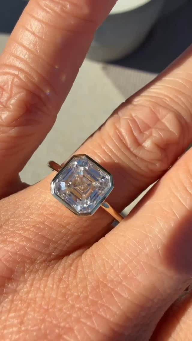 Gold engagement ring with a large emerald-cut diamond on a person's finger
