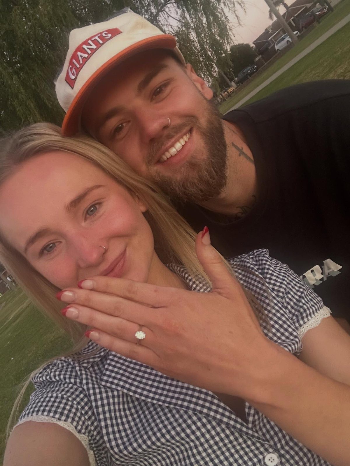 Smiling couple posing for a selfie with a diamond engagement ring visible