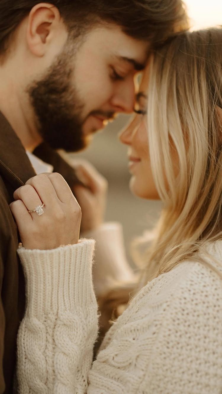 Couple touching foreheads with a diamond engagement ring visible on the woman's hand.